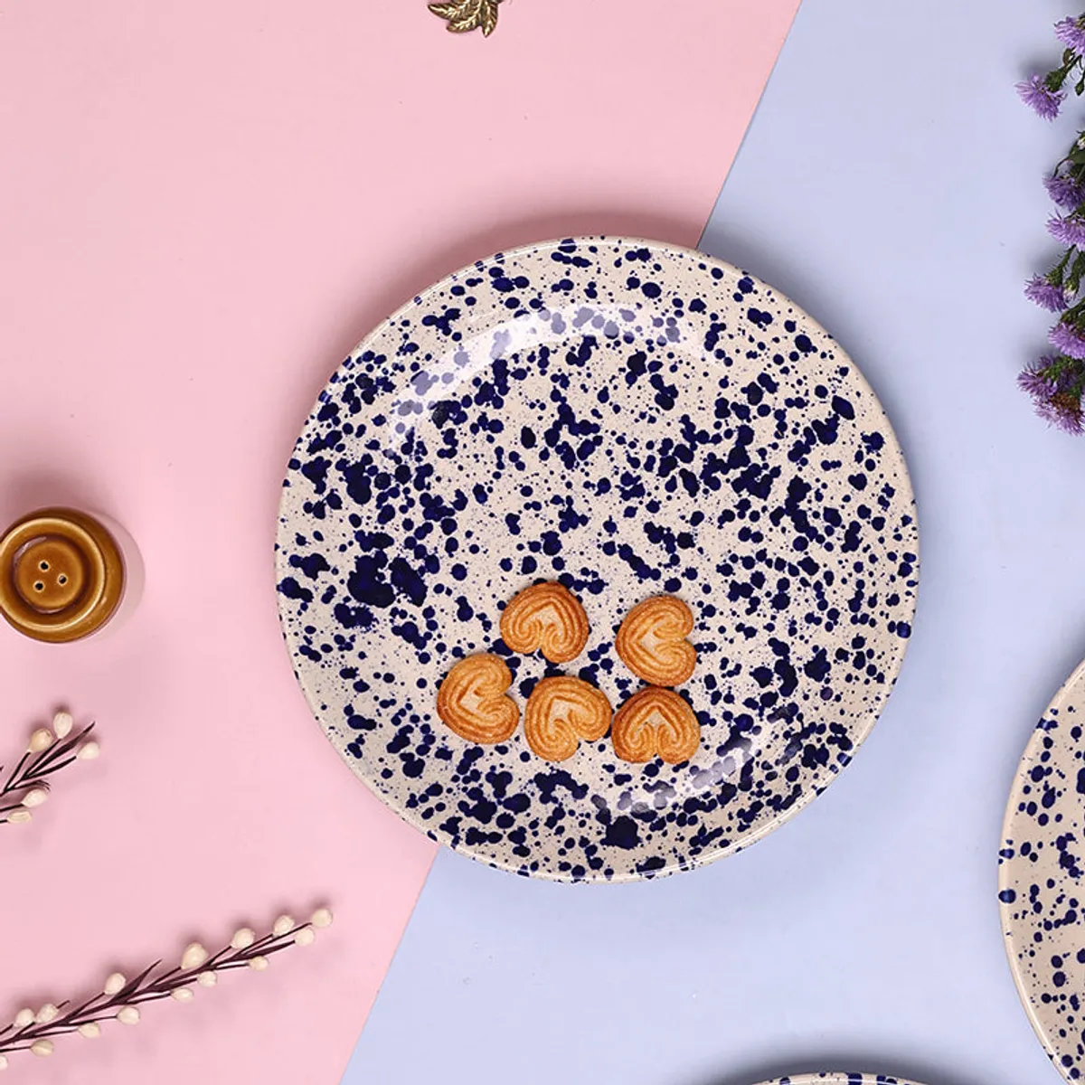 Blue splatter ceramic dinner plate with biscuits on a pink and blue backdrop