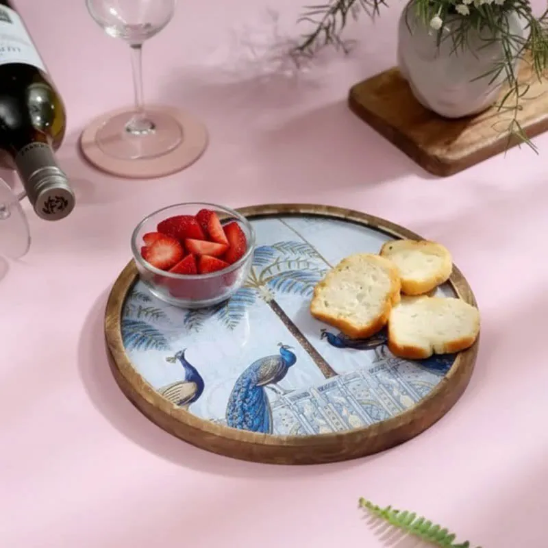 Blue peacock platter presented with strawberries and bread on a pink table