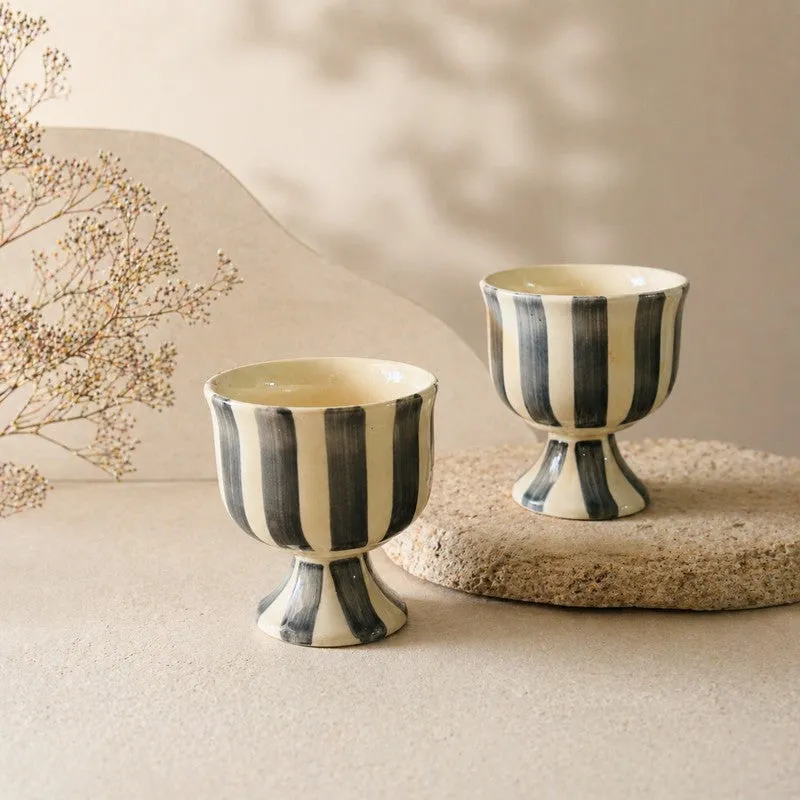Two striped ceramic dessert cups styled on a textured neutral surface