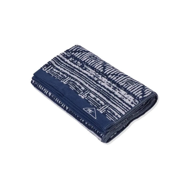 Folded blue bath towel with contrasting woven design on a white background