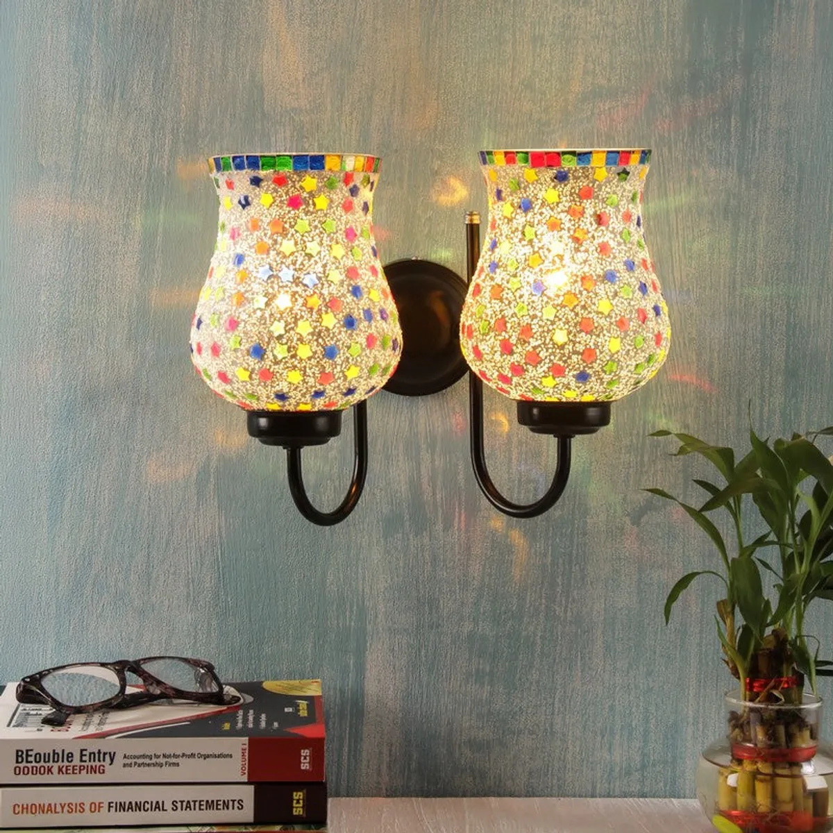 Lit double wall lamp with multicolour glass shades mounted on a blue wall
