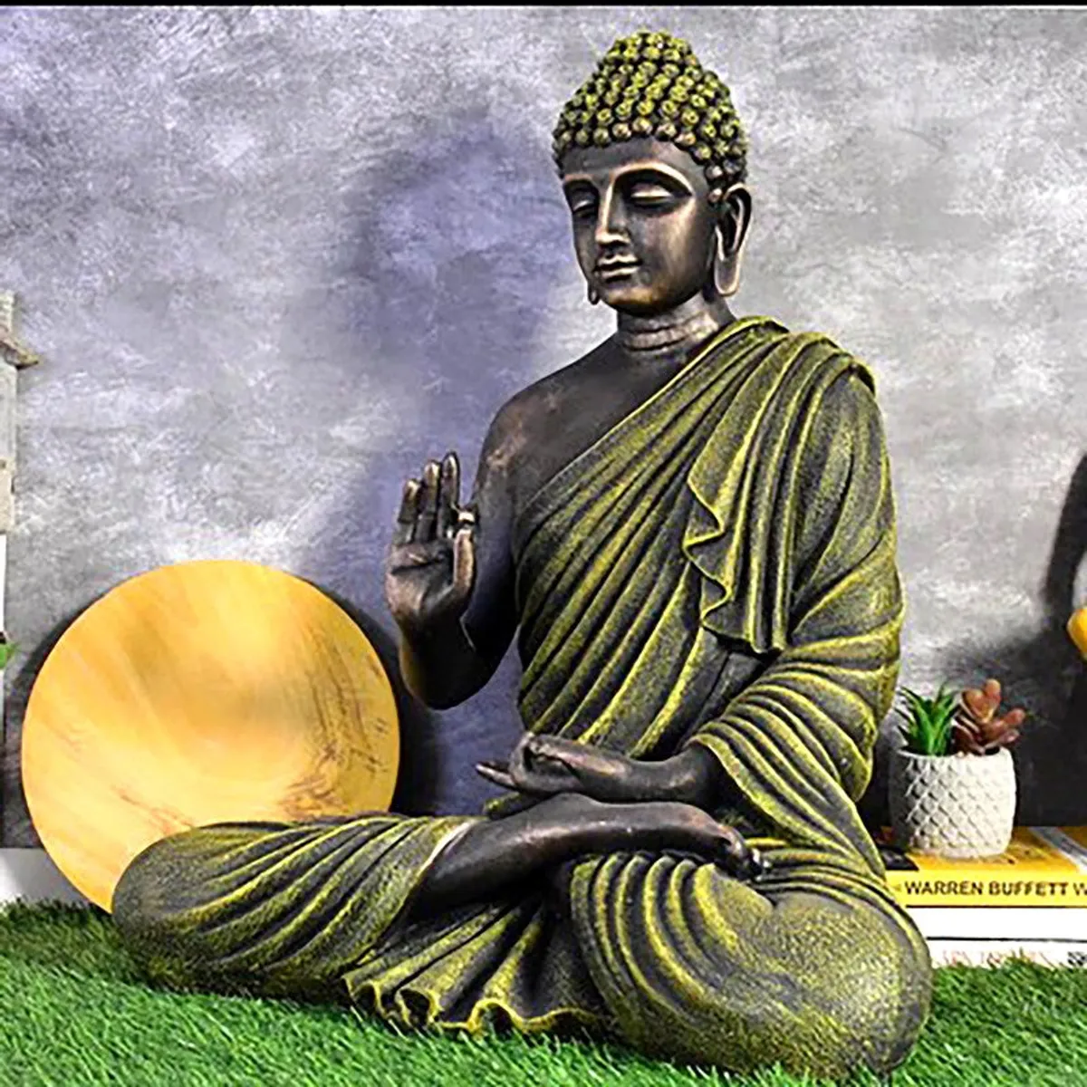 Side view of a seated Buddha idol in grey and olive green