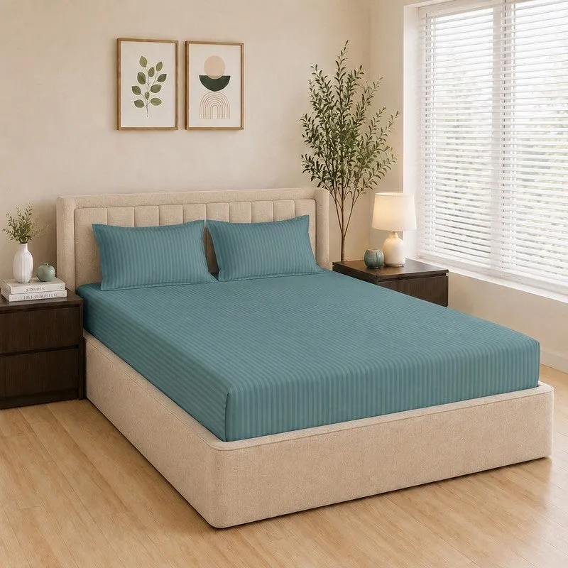 Teal striped fitted bedsheet styled on a double bed with two matching pillow covers