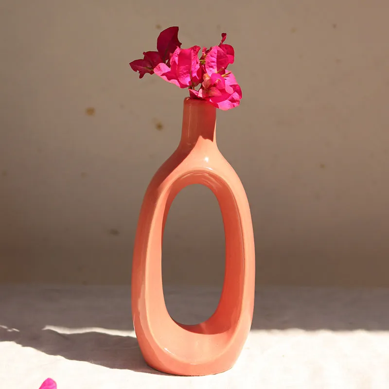 Pink ceramic donut vase with bright pink flowers in sunlight