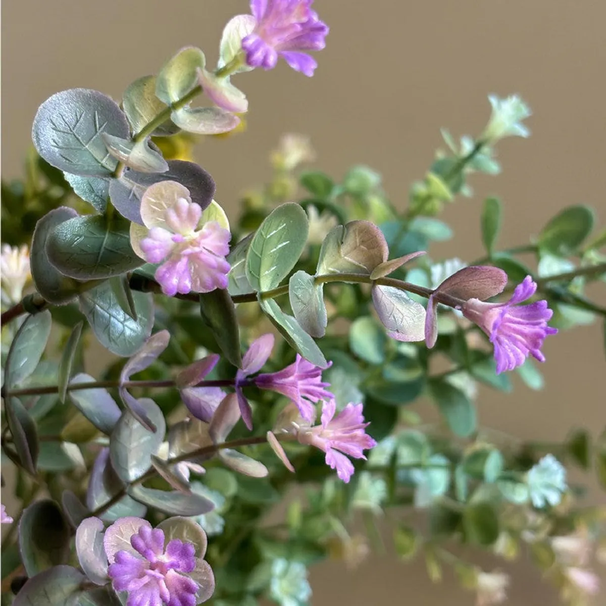 Close-up of purple artificial flowers and rounded eucalyptus leaves
