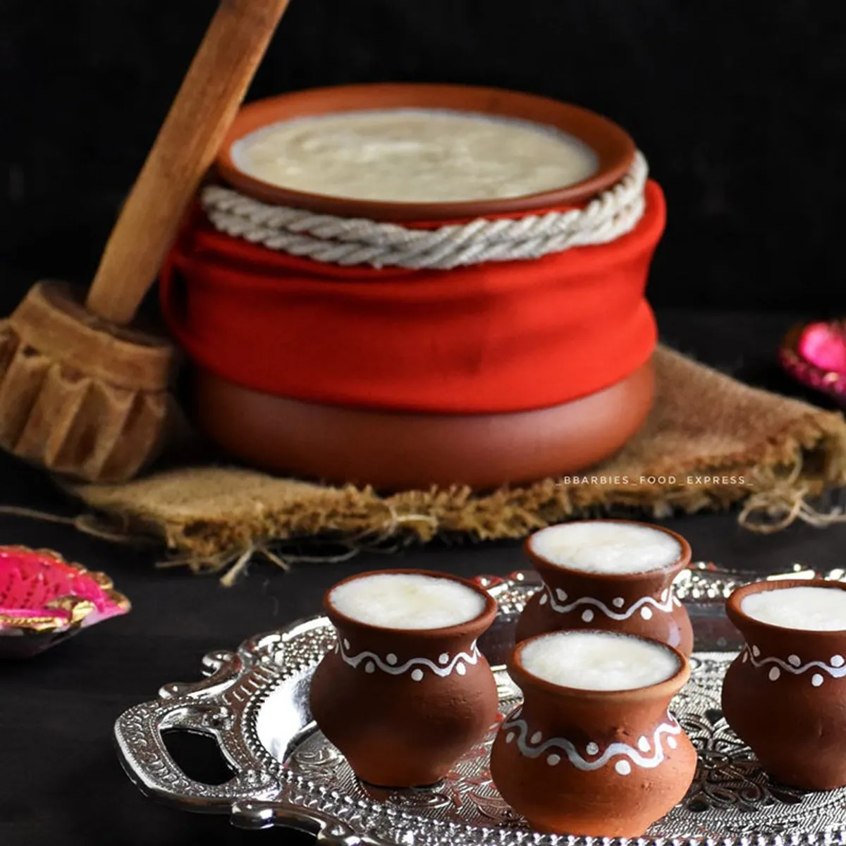 Terracotta handi with lid and small serving pots on a festive tray