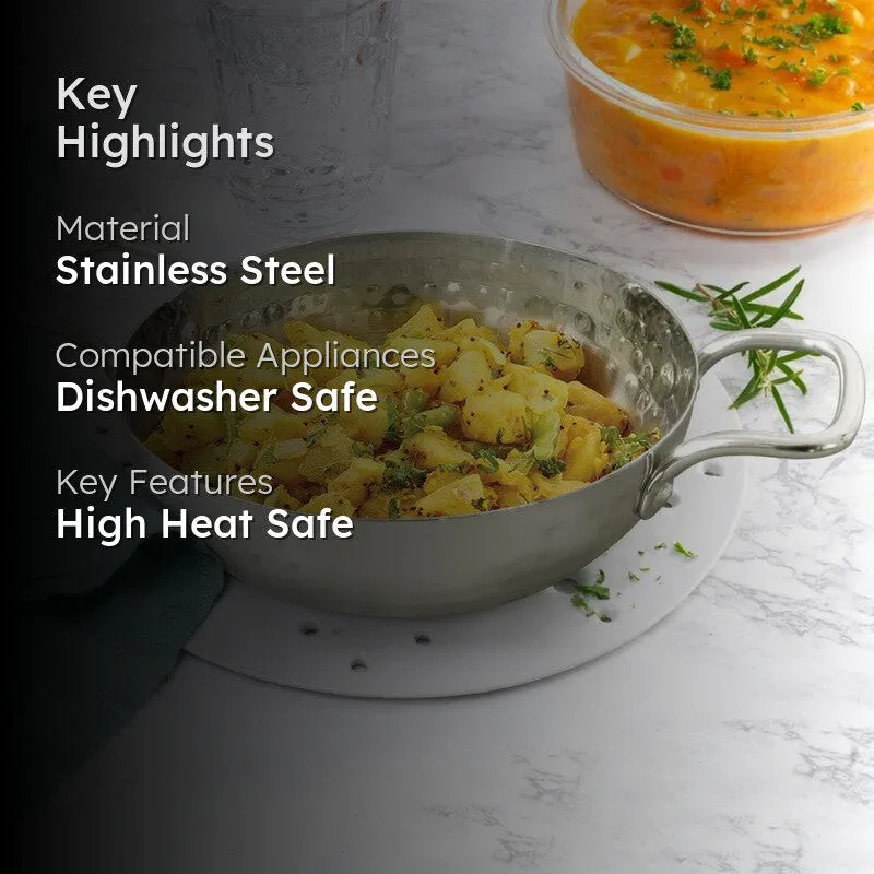 Silver hammered kadhai filled with cooked vegetables beside a bowl of curry