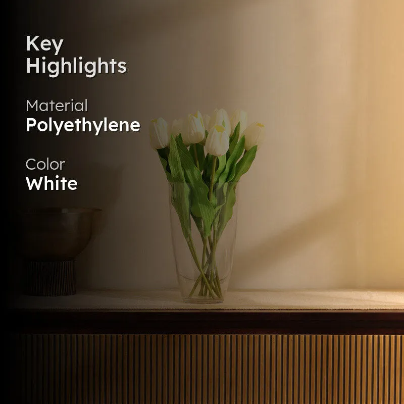 White artificial tulips and green leaves styled in a vase indoors