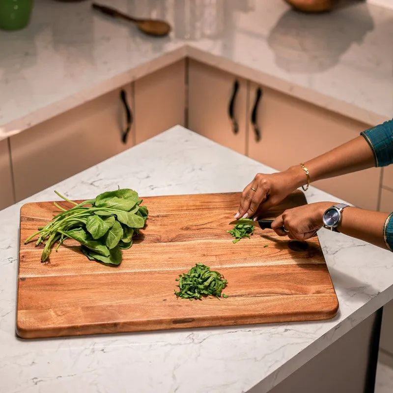 Person chopping greens on a large natural wood board