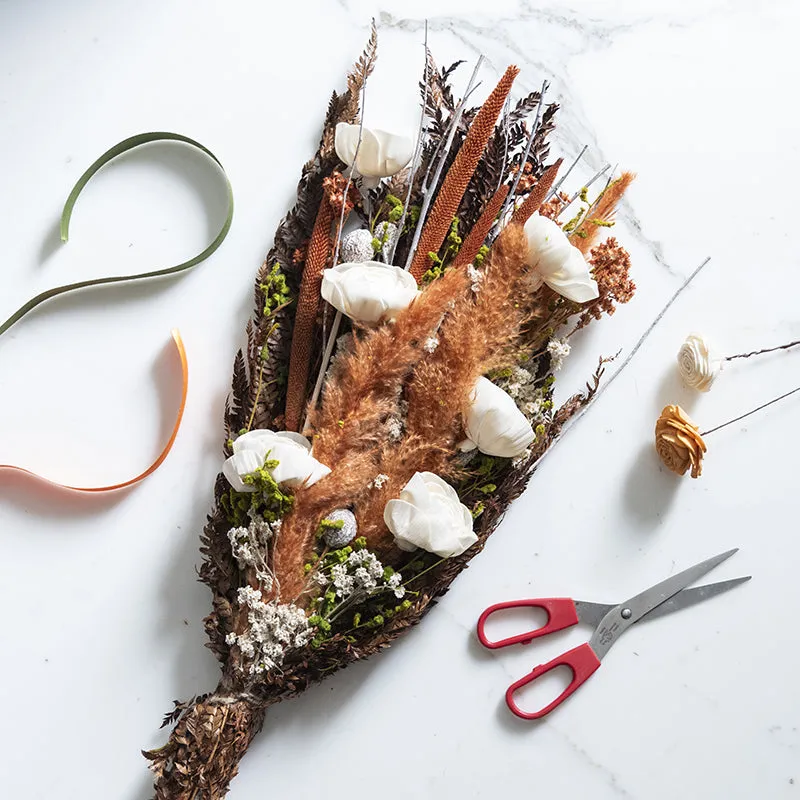Flat lay of a dried flower bouquet with white blooms and rust-toned grasses