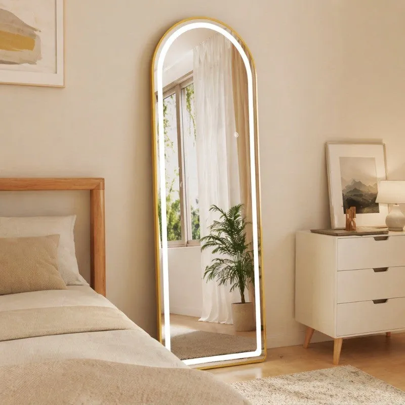 Gold arched LED mirror standing beside a bed and white dresser
