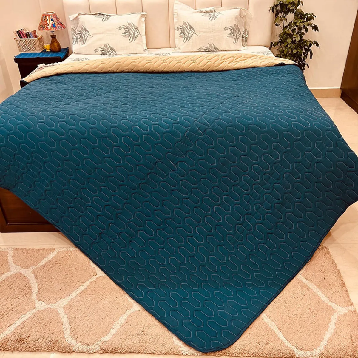 Teal comforter with geometric quilted pattern covering a double bed.