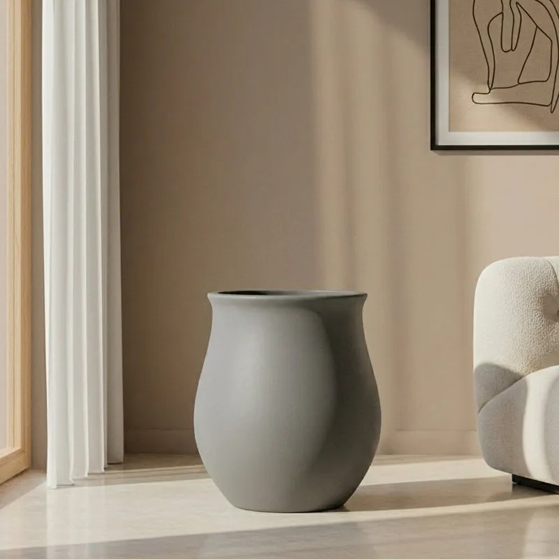 Grey matte floor planter shown empty beside a light-coloured armchair