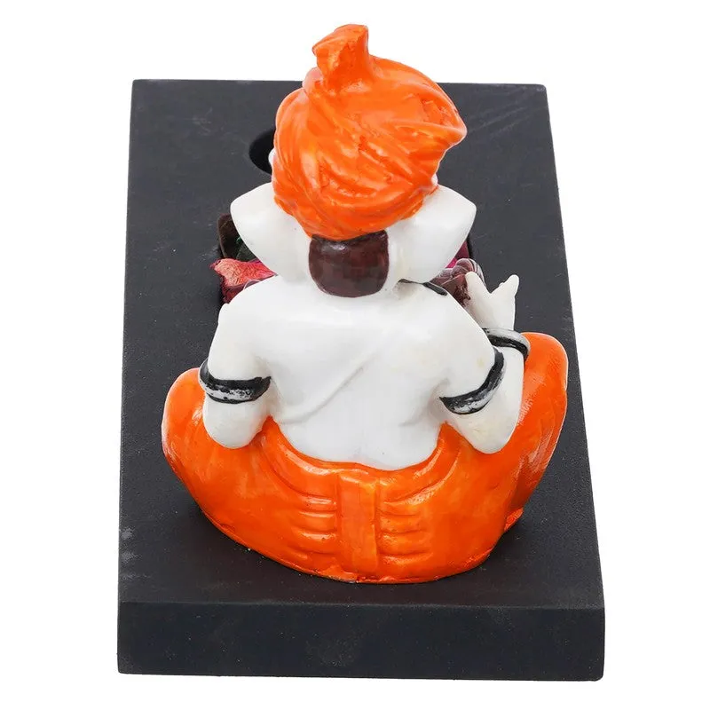 Back view of orange and white Ganesha figurine on black candle holder base