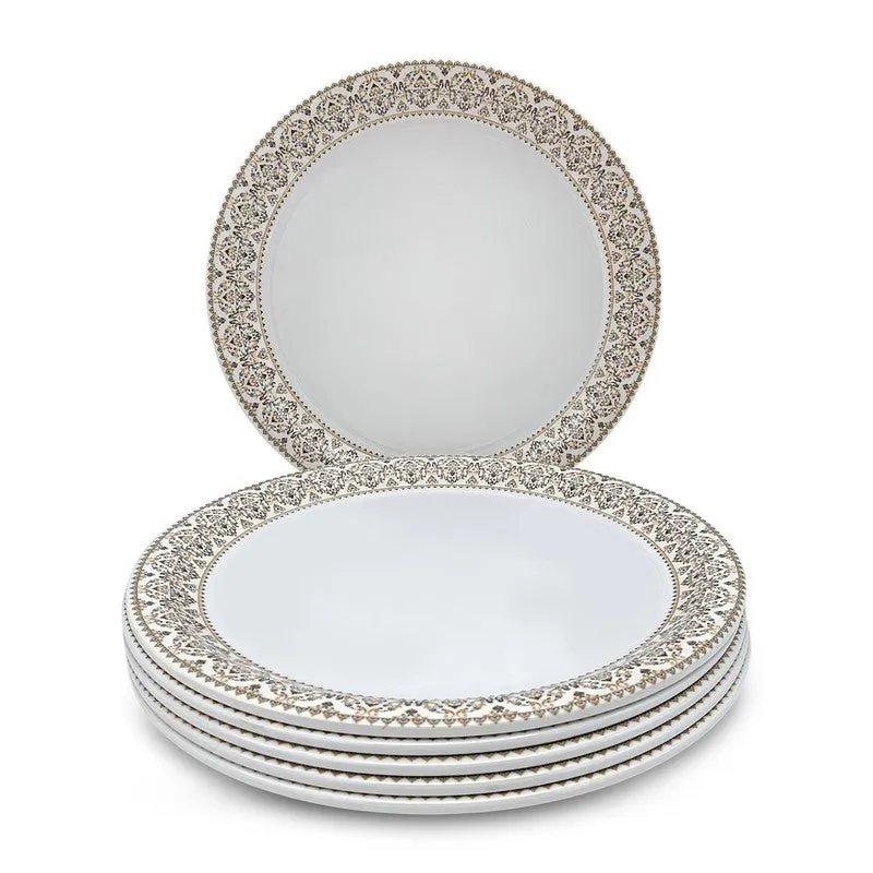 Six white dinner plates with ornate patterned rims stacked with one upright plate