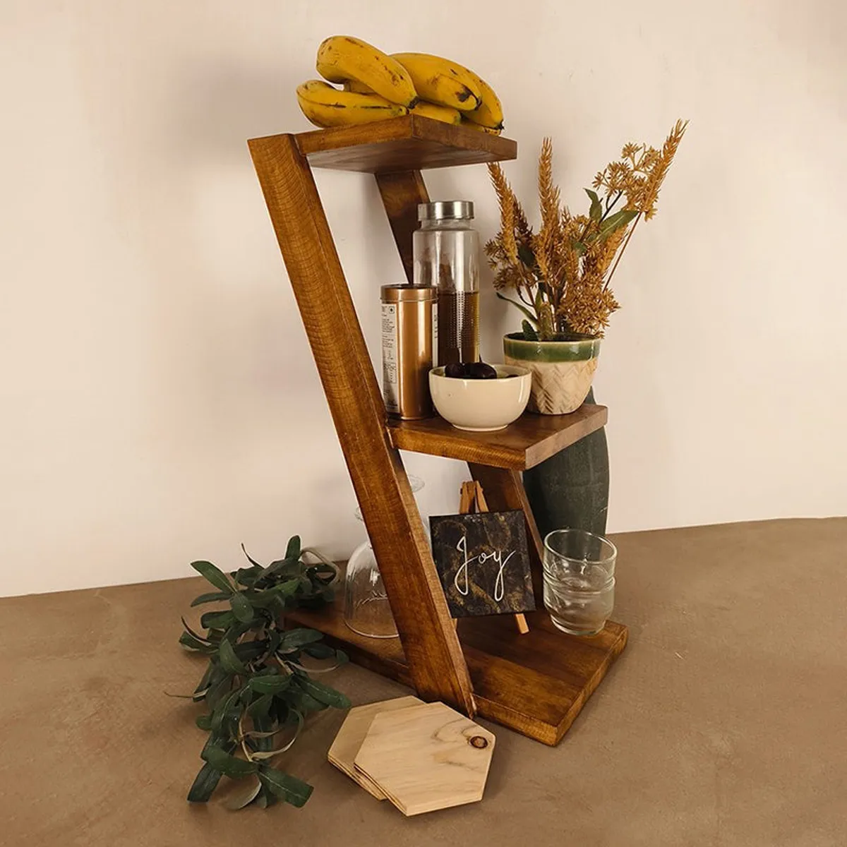 Brown three-tier wooden rack styled with fruit, jars and decor