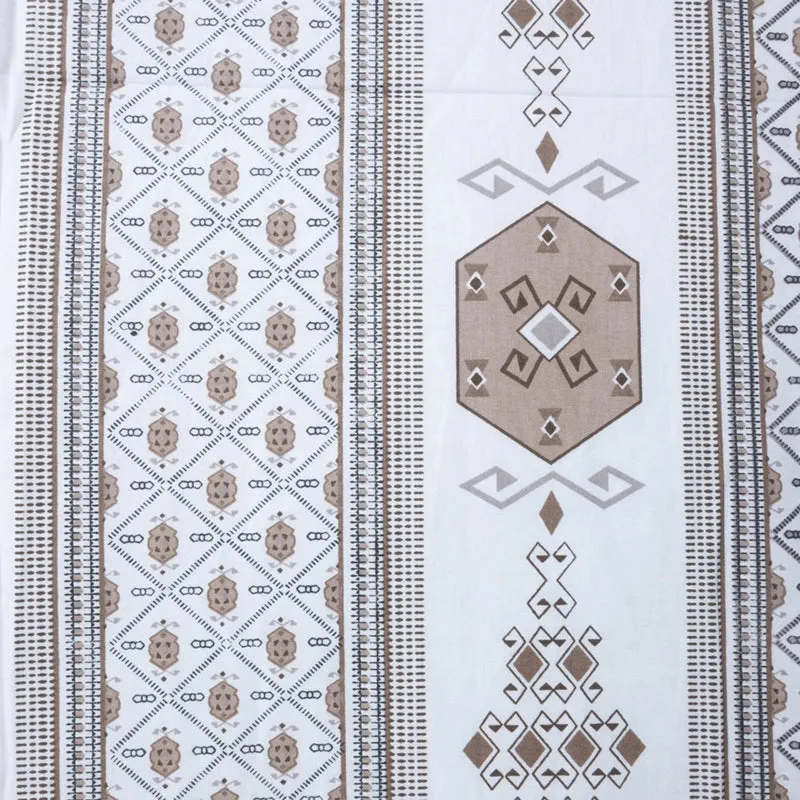 Flat lay close-up of the bedsheet print with brown geometric motifs and striped borders.