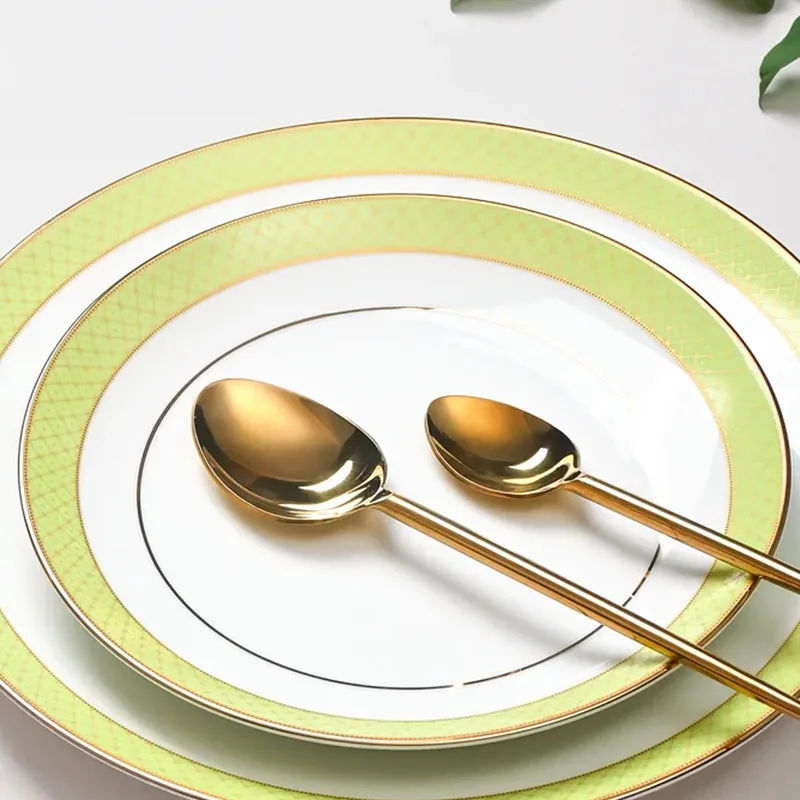 Close-up of white plates with green patterned rims and gold detailing