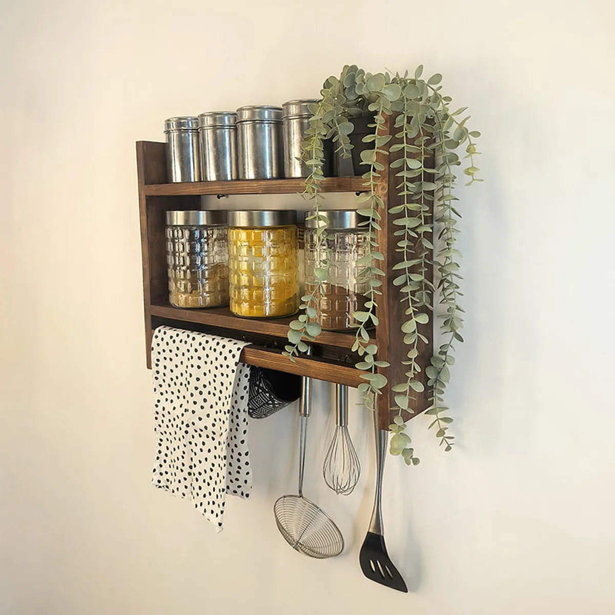 Brown wooden kitchen storage rack with jars, tins, hooks and hanging utensils