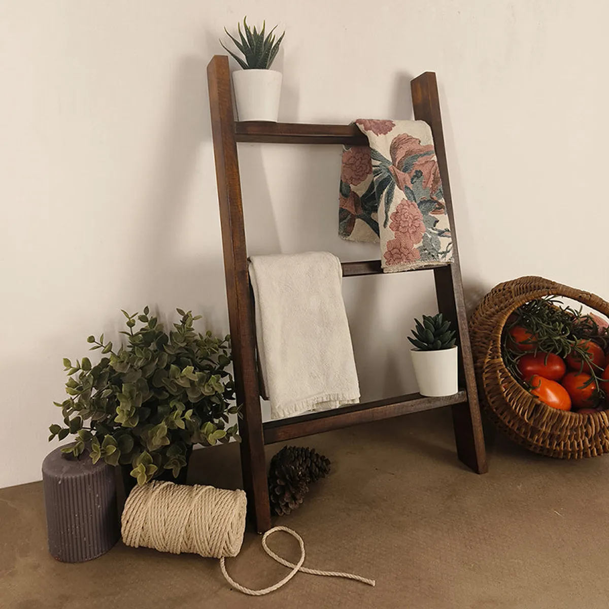 Angled view of a brown wooden ladder-style rack styled with towels and plants