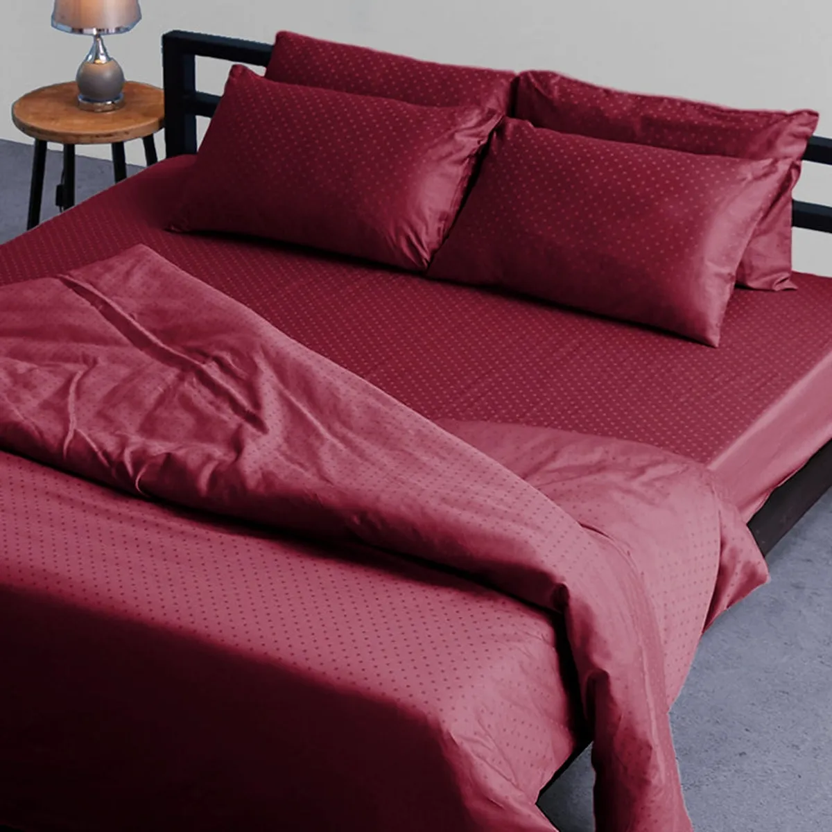 Maroon duvet cover draped over a bed with matching cushions