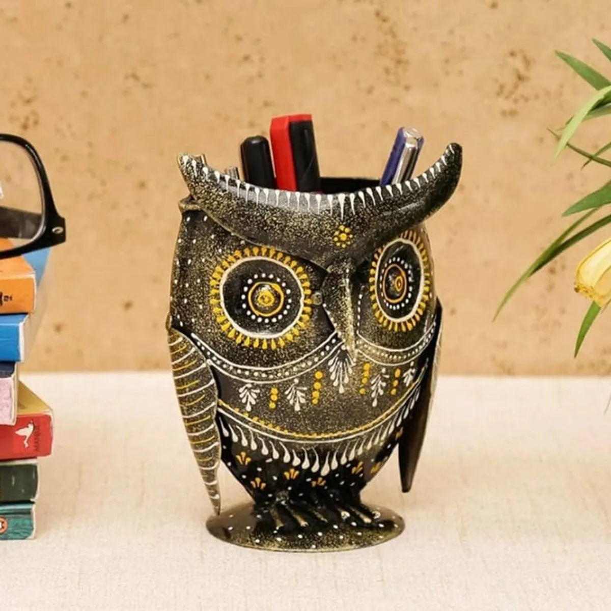 Angled view of an owl pen stand holding pens beside books and glasses