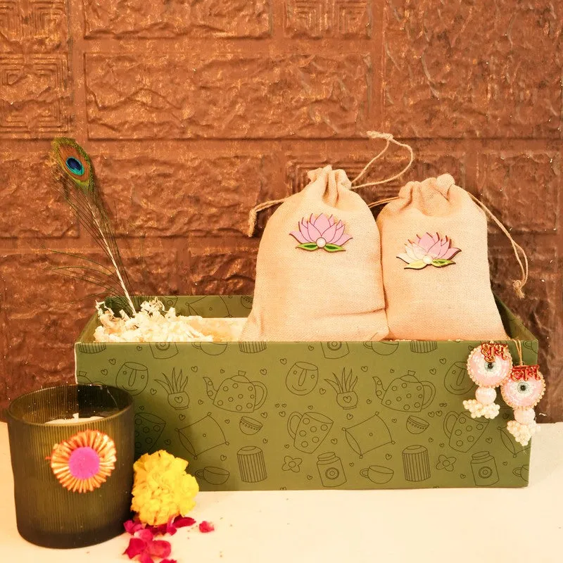 Festive gift box with two potlis, candle and peacock-feather accent