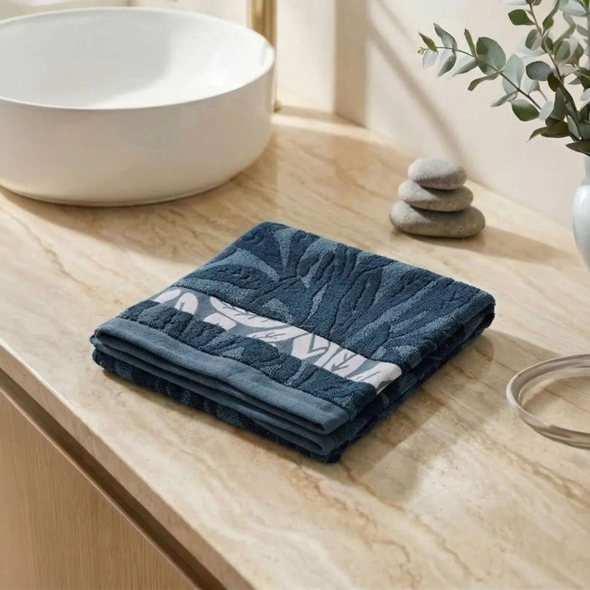 Folded blue floral bath towel placed beside a bathroom basin