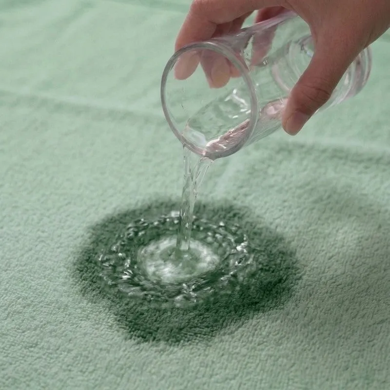 Water being poured onto sage green towel fabric