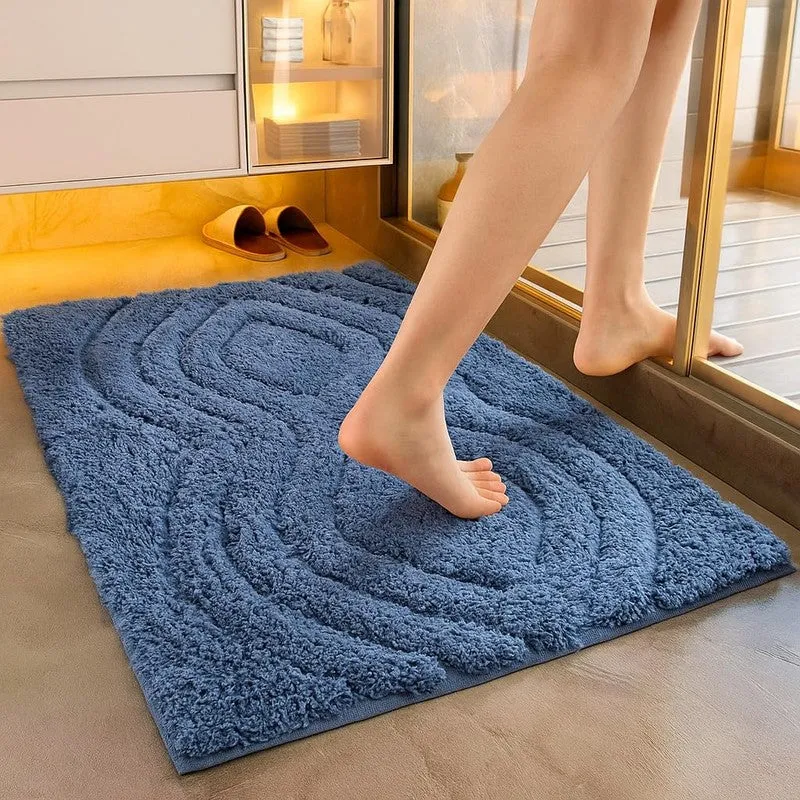 Blue textured geometric bath mat placed beside a glass shower enclosure