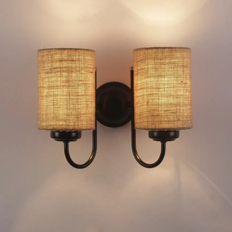 Front view of lit dual jute wall lamp on a plain wall