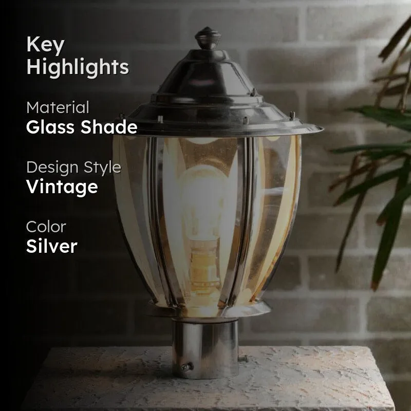 Silver outdoor gate lamp with clear glass shade, lit against a brick wall