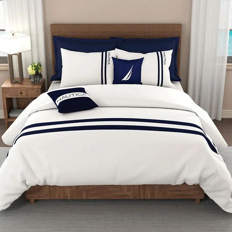 White and navy striped bedding styled on a bed in a bright bedroom