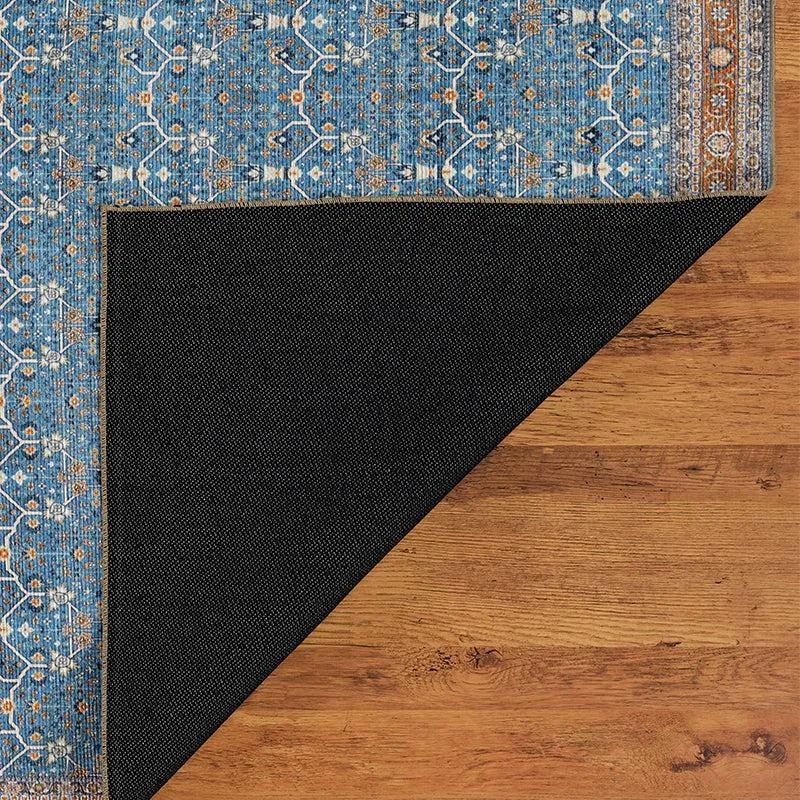 Corner of blue patterned carpet with black underside flipped over on wooden floor
