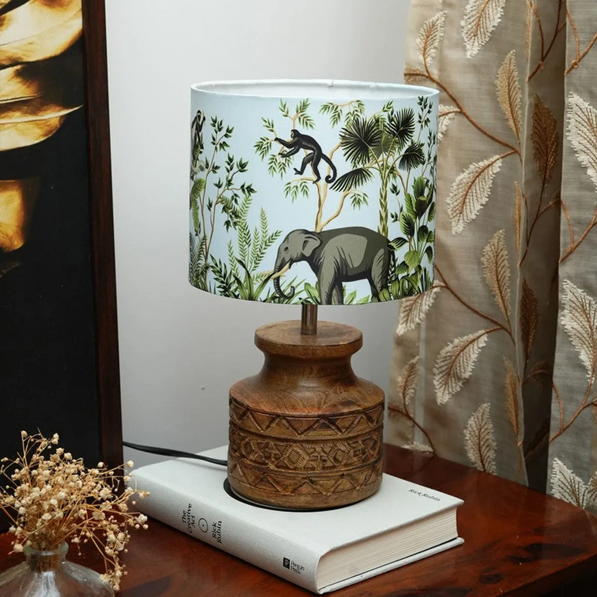 Close view of table lamp with carved wooden base and jungle-themed shade