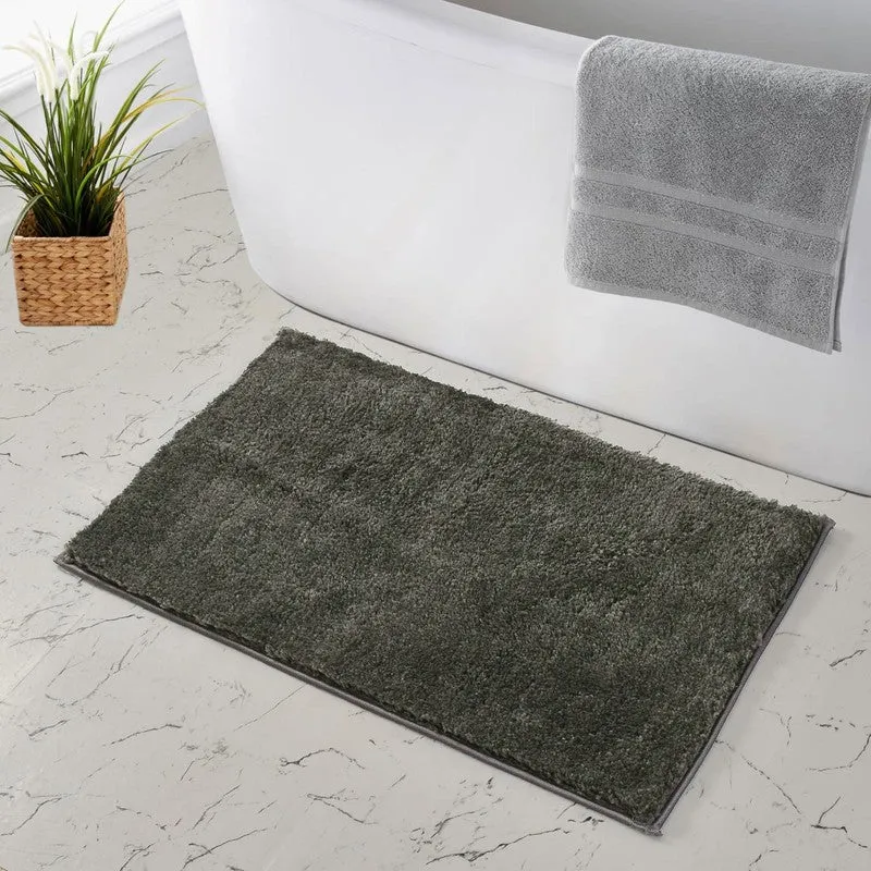 Grey rectangular bath mat beside a bathtub on a tiled floor