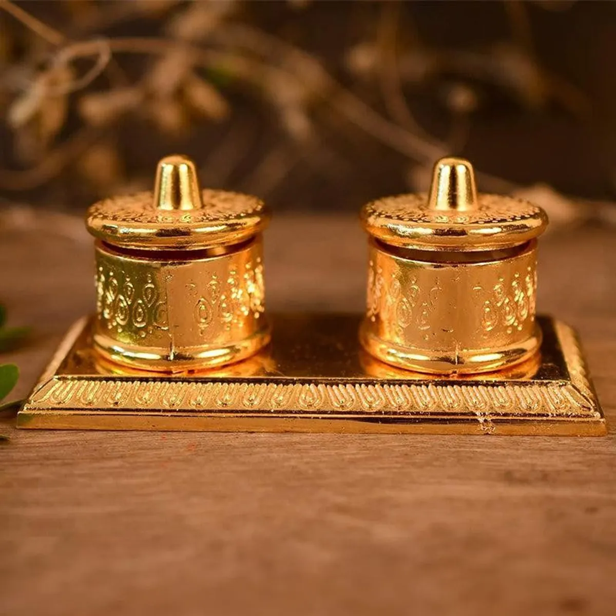 Front view of a gold tray with two matching embossed lidded containers