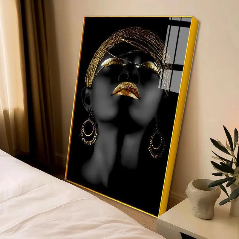 Framed black and gold portrait wall art leaning beside a bed