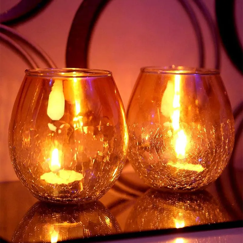 Pair of golden glass tealight holders with lit candles and reflective glow