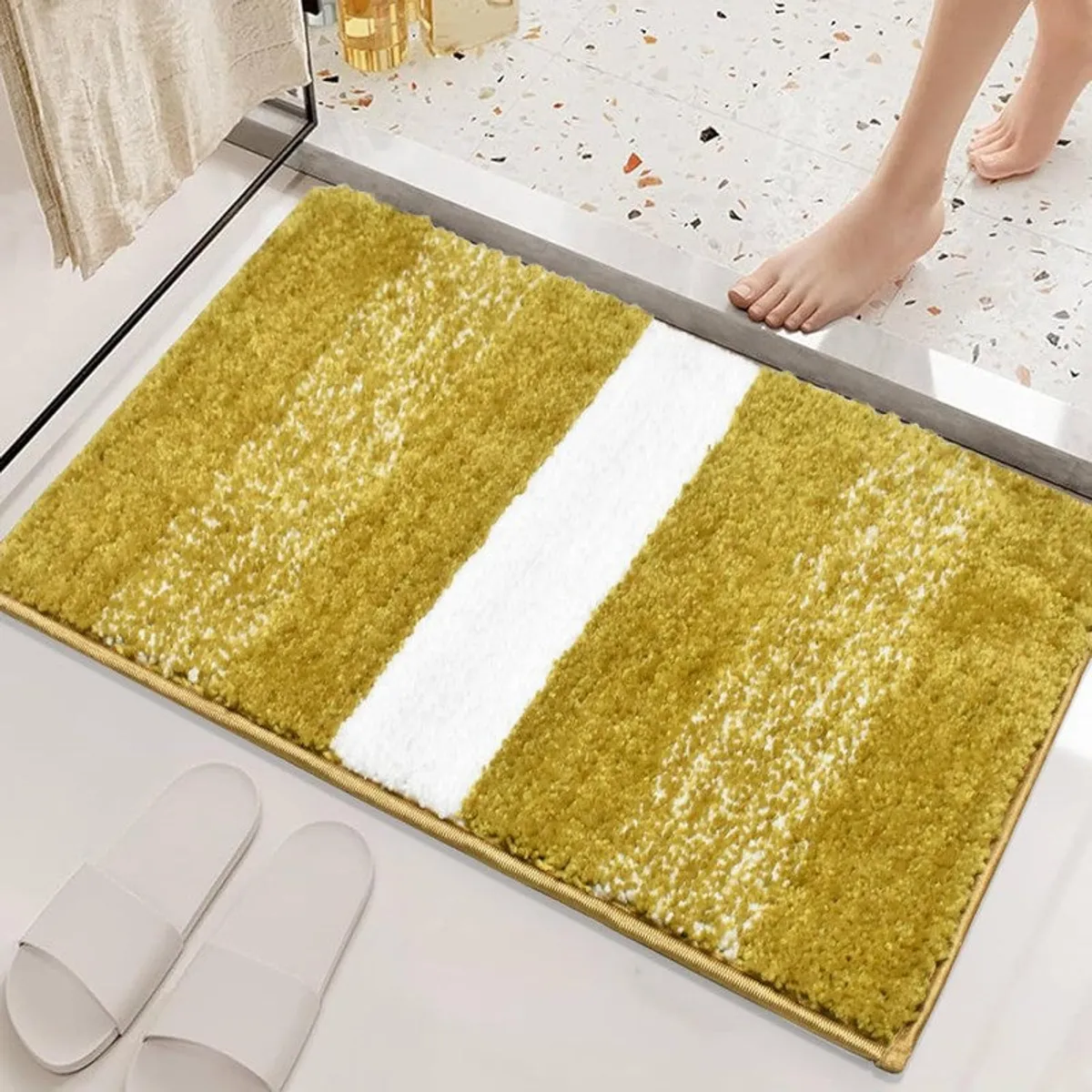 Yellow bath mat with a white centre stripe placed near a shower step