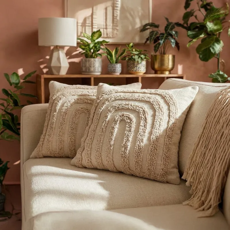 Two off-white tufted cushion covers styled on a beige sofa in a warm room.