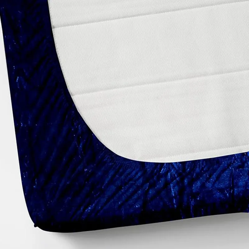 Corner view of a dark blue fitted bedsheet with white underside