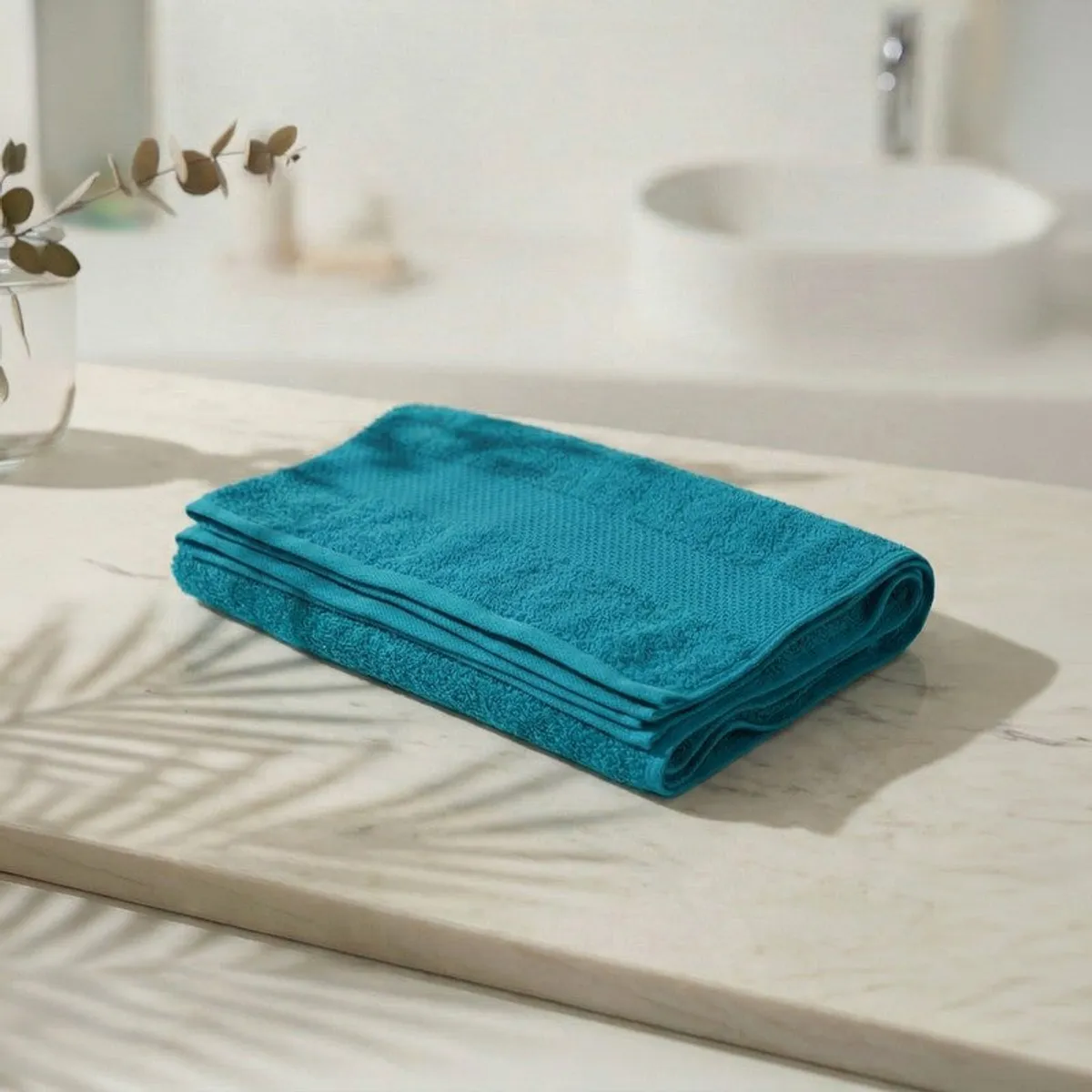 Folded teal bath towel displayed on a marble bathroom counter