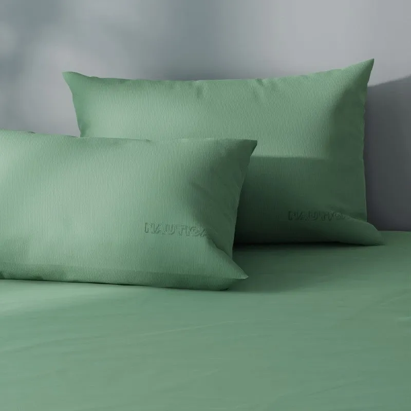 Green cotton bedding with matching pillows and subtle embroidered branding