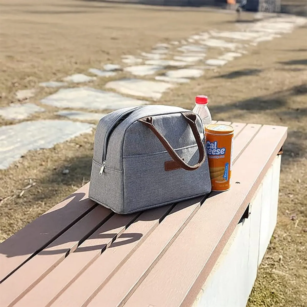 Grey lunch bag placed on a park bench outdoors