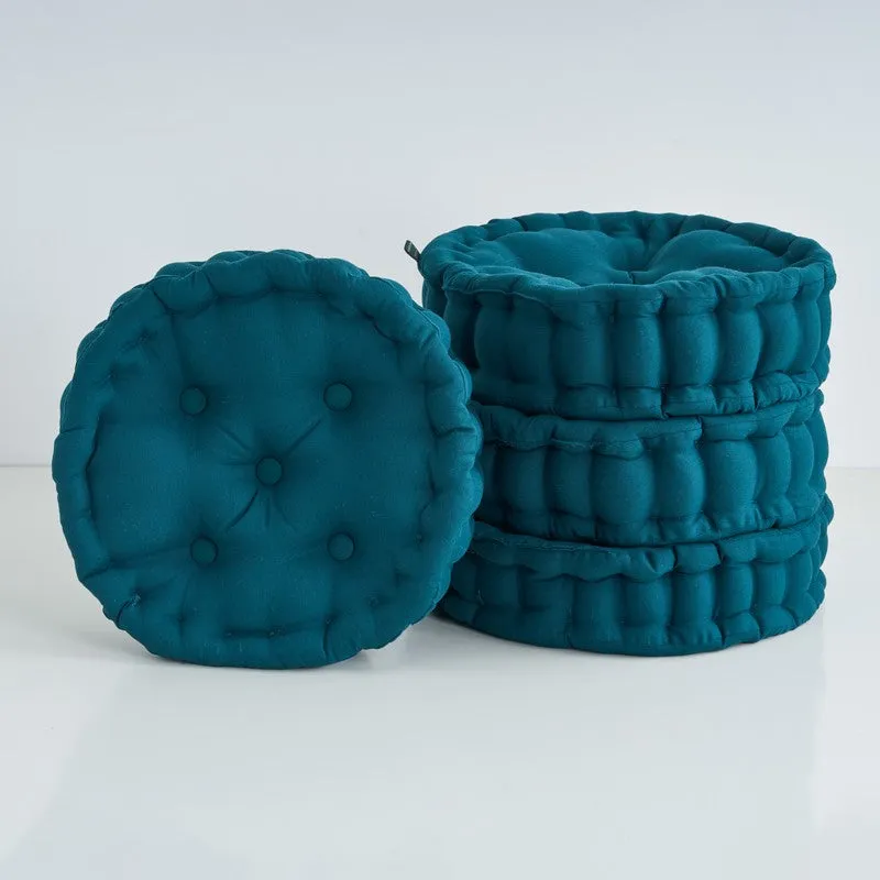 Set of four round green floor cushions stacked together
