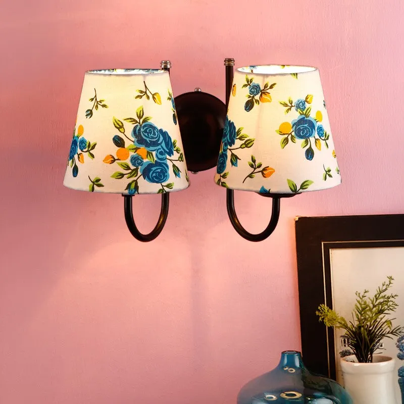 Twin wall lamp with blue floral shades mounted on a pink wall
