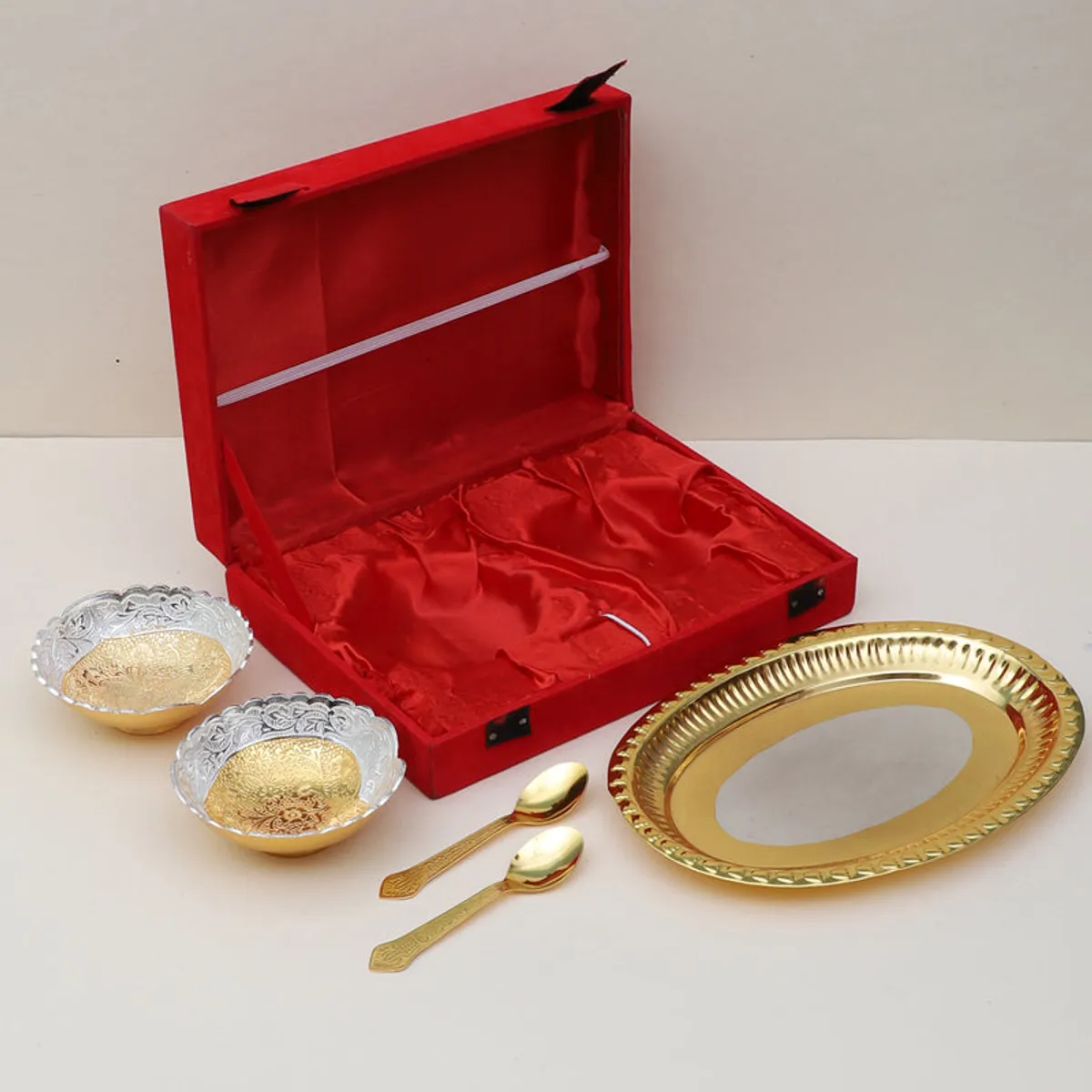 Gold tray, two floral dessert bowls and two spoons displayed beside an open red case