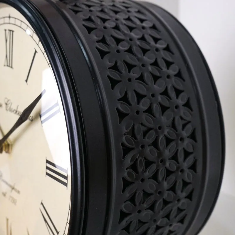 Close-up of the clock's black floral lattice side detailing and Roman numeral face.