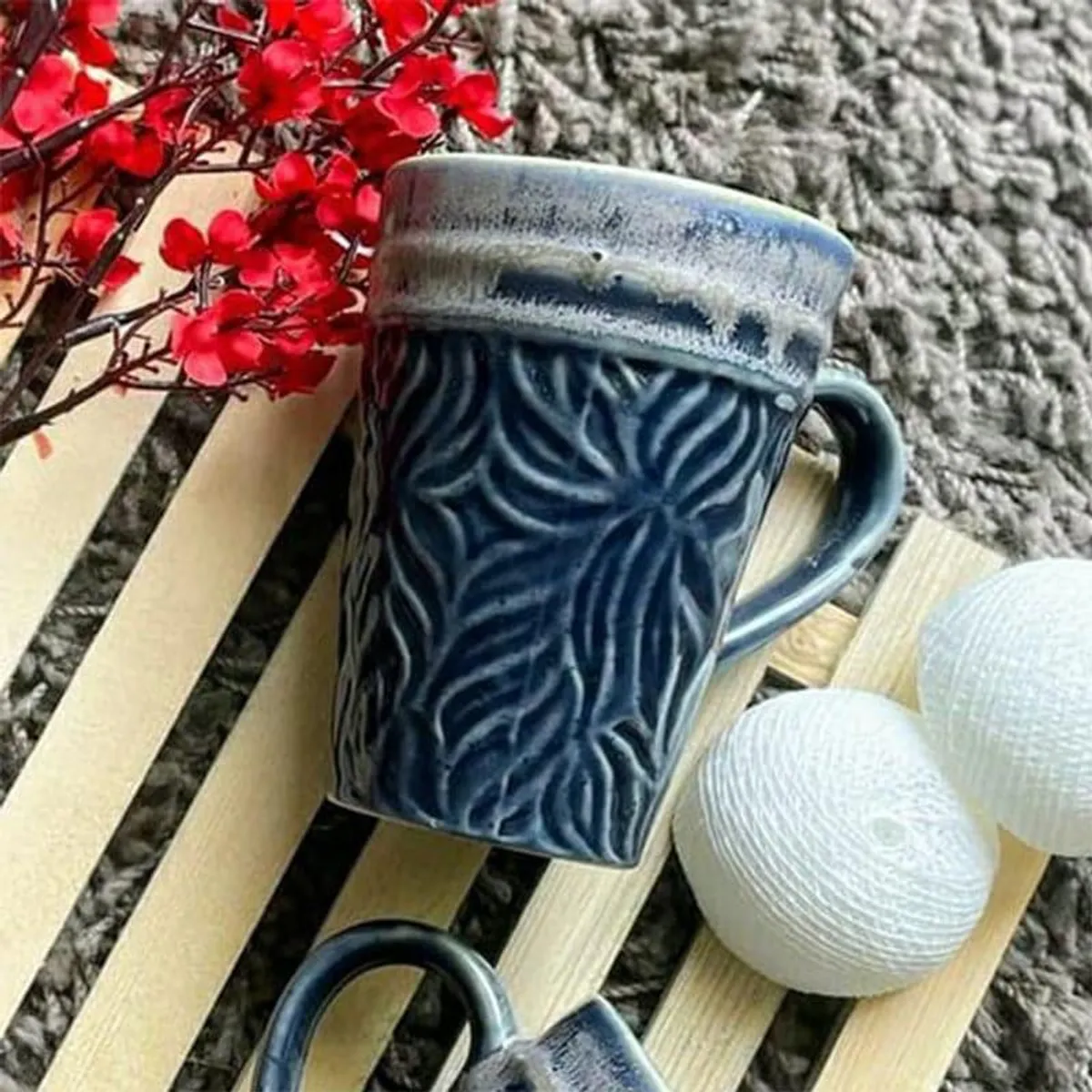 Close-up of a dark blue mug with leafy texture and a contrasting glossy rim